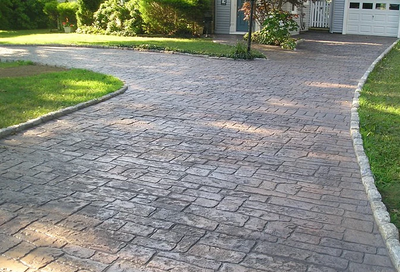 Long and bordered driveway stamped to look like brick pavers that are weathered.
