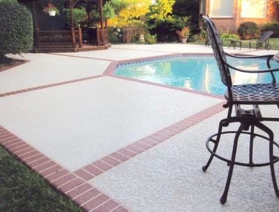 Concrete pool deck with stamped border that is stamped like brick pavers.
