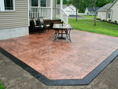 Backyard patio done with stamped and stained concrete, with decorative edging.