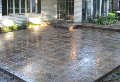 Polished stamped concrete patio with one step up to a sliding glass door into house.