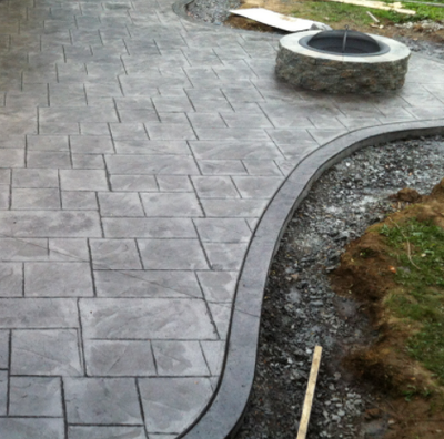 Gray stamped patio with round fire pit built right in.