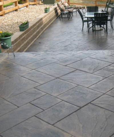 Multiple shades of brown concrete patio stamped to look like square ceramic tiles.